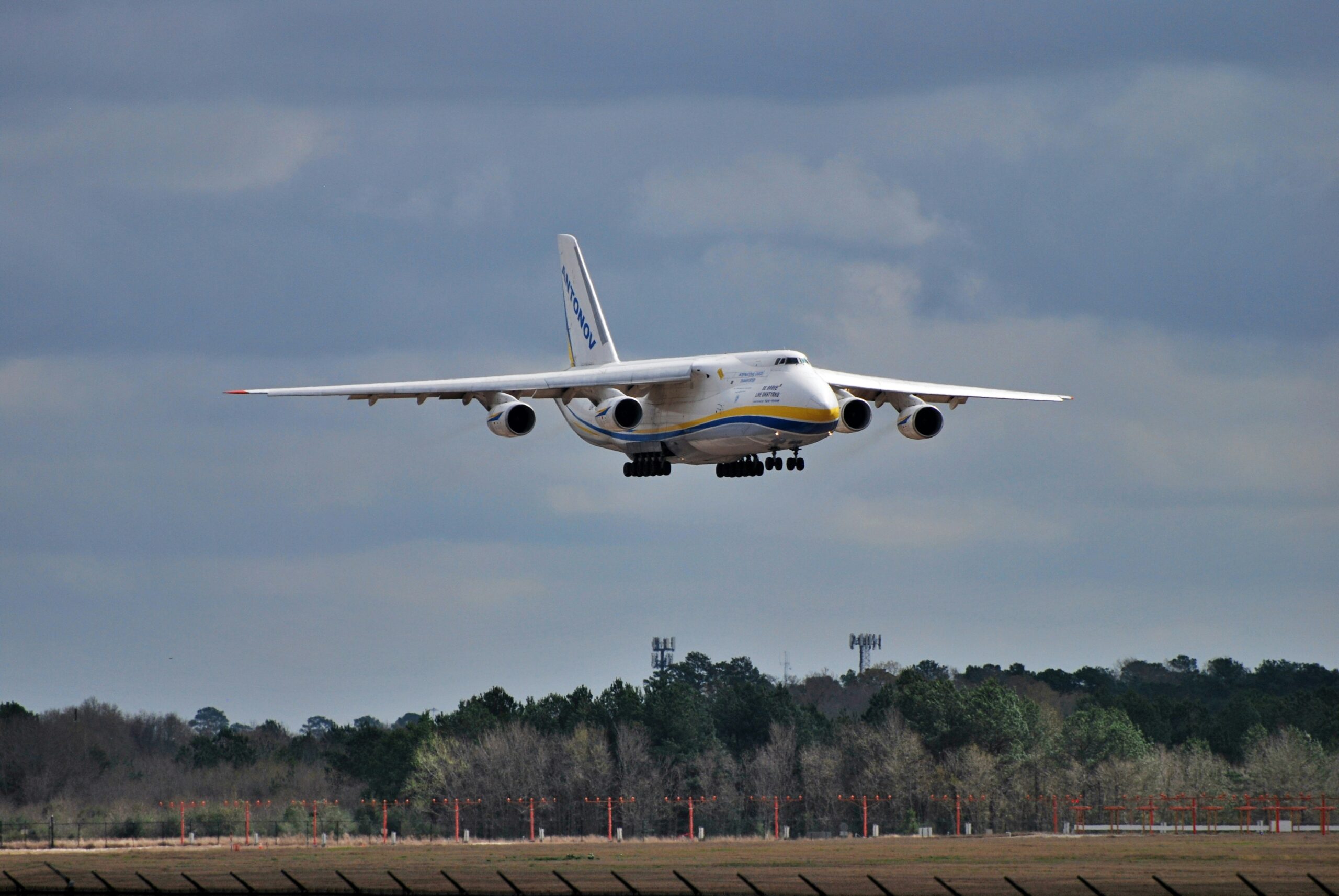 Potężny samolot transportowy Antonov podchodzący do lądowania nad linią drzew.